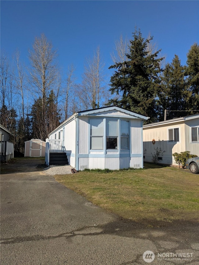 manufactured / mobile home with an outdoor structure, a front lawn, and a storage shed