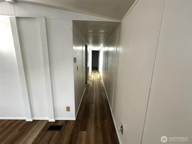 corridor with dark wood-type flooring, visible vents, and baseboards