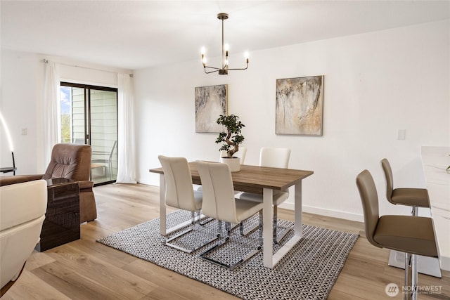 dining space featuring an inviting chandelier, light wood-style floors, and baseboards