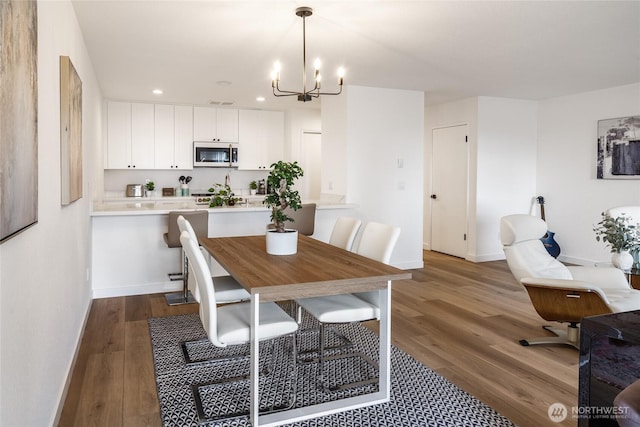 dining area with dark wood-type flooring, baseboards, recessed lighting, and a chandelier