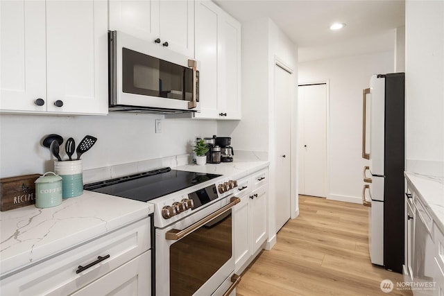 kitchen with white cabinets, light wood-style flooring, light stone countertops, and white appliances