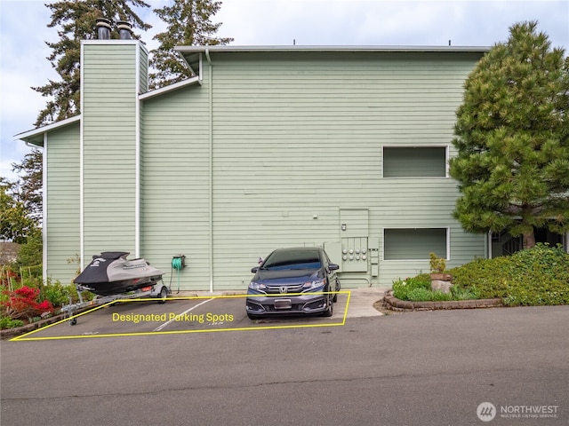view of side of property featuring a chimney and uncovered parking