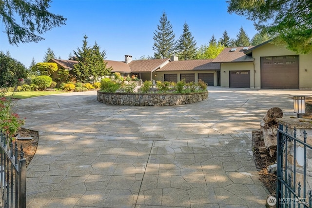 ranch-style home with a chimney, concrete driveway, and a garage