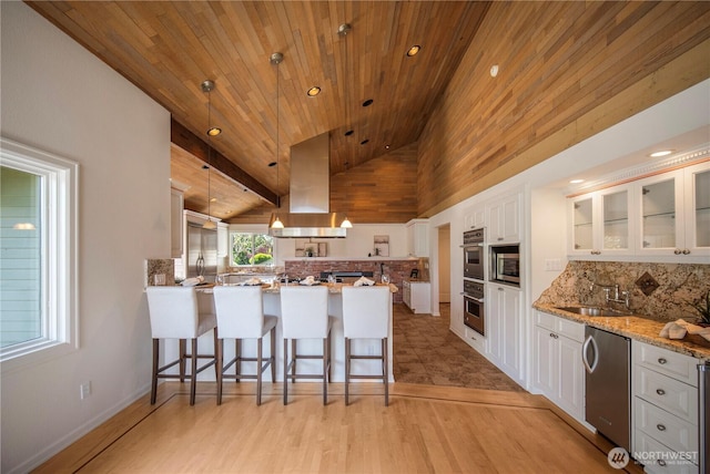 kitchen with island exhaust hood, a peninsula, backsplash, and stainless steel appliances