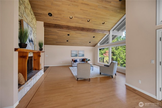 living area featuring a fireplace, beam ceiling, wood ceiling, and baseboards
