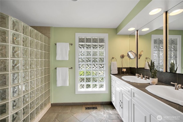 bathroom with double vanity, baseboards, recessed lighting, and a sink
