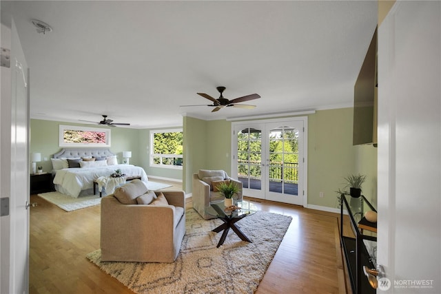 living room featuring wood finished floors, a ceiling fan, baseboards, ornamental molding, and french doors