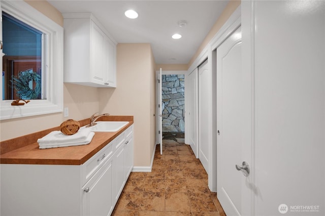 interior space featuring recessed lighting, stone finish floor, and vanity