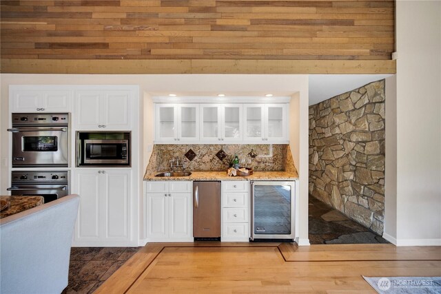 bar with stainless steel appliances, backsplash, a sink, a bar, and wine cooler