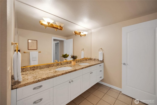 full bath with double vanity, a sink, tile patterned floors, and baseboards