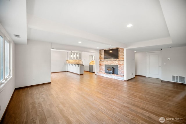 unfurnished living room with baseboards, visible vents, light wood-type flooring, and a wealth of natural light