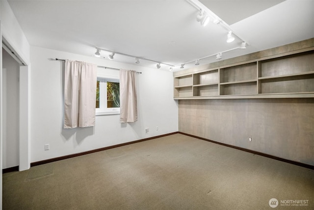 carpeted empty room with rail lighting and baseboards