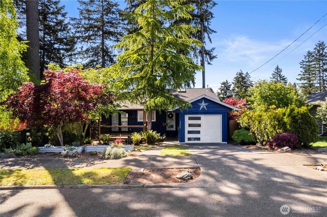 obstructed view of property featuring an attached garage, concrete driveway, and a porch