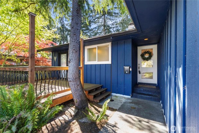 property entrance with board and batten siding and a wooden deck