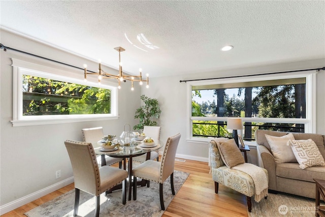 dining room with a textured ceiling, healthy amount of natural light, baseboards, light wood-style flooring, and recessed lighting