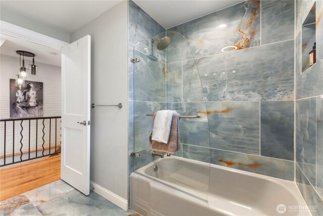 bathroom with bathtub / shower combination, marble finish flooring, and baseboards