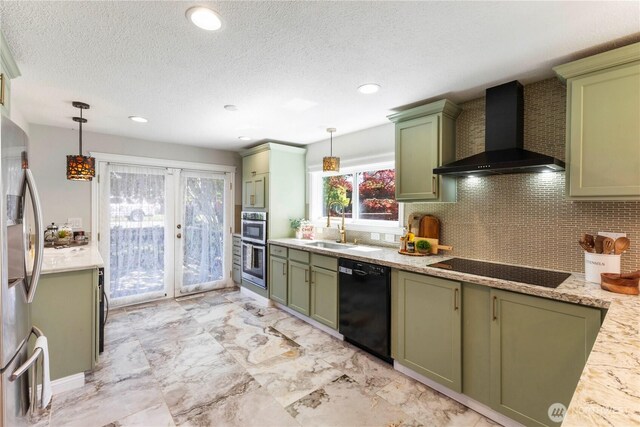 kitchen with green cabinets, wall chimney range hood, black appliances, a sink, and backsplash