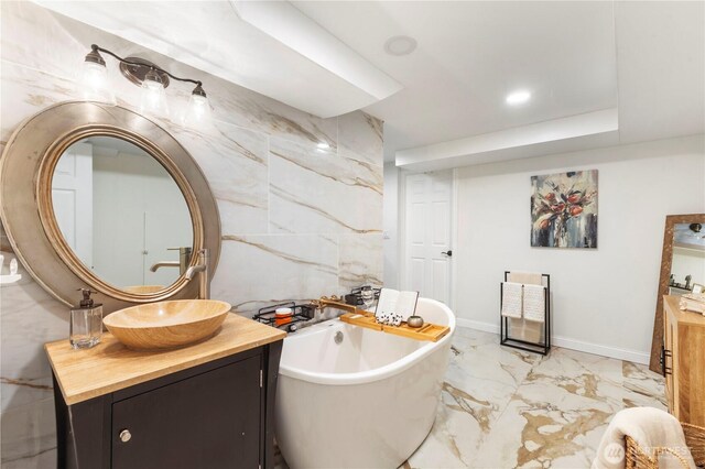 bathroom with vanity, marble finish flooring, and a soaking tub