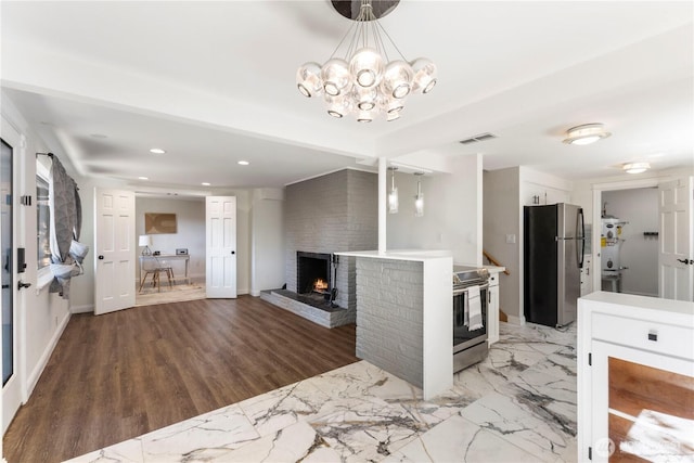 kitchen featuring stainless steel appliances, a brick fireplace, recessed lighting, white cabinetry, and light countertops