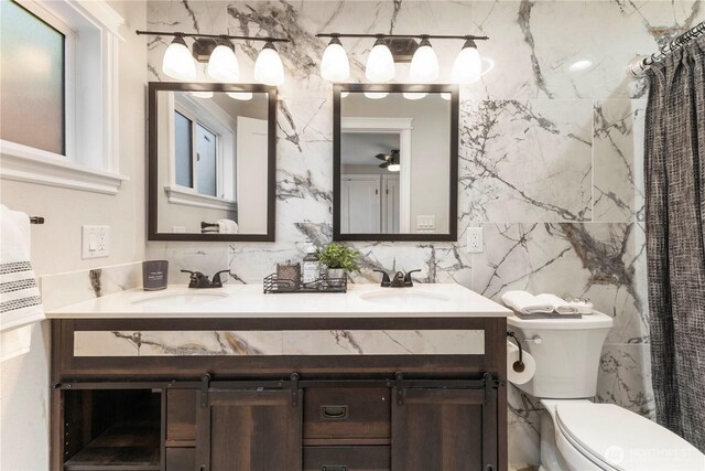 full bath featuring tile walls, toilet, and double vanity