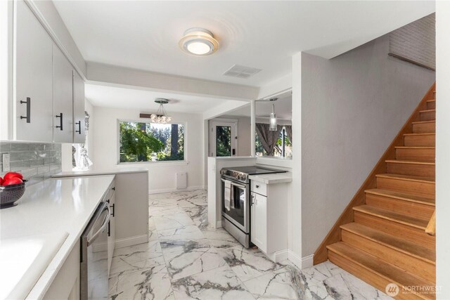 kitchen featuring stainless steel appliances, light marble finish floors, baseboards, decorative backsplash, and light countertops