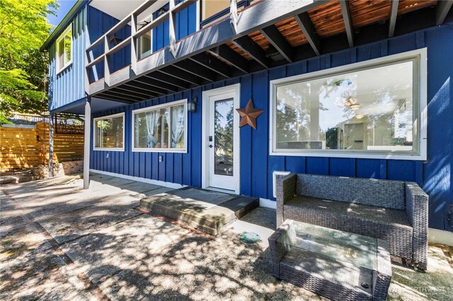 doorway to property featuring board and batten siding and fence