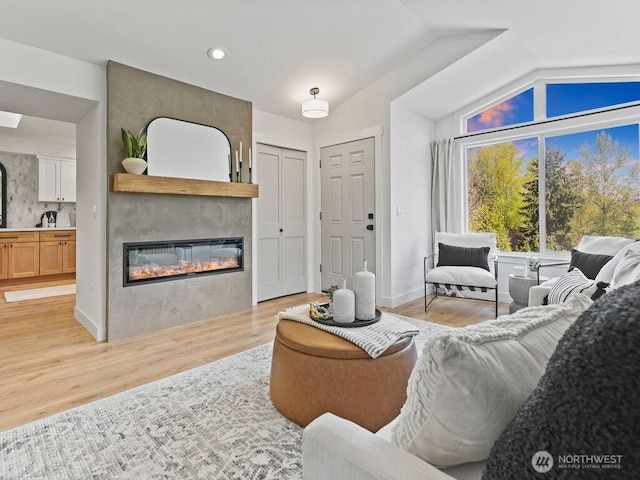 living area with lofted ceiling, a large fireplace, light wood-style floors, and recessed lighting