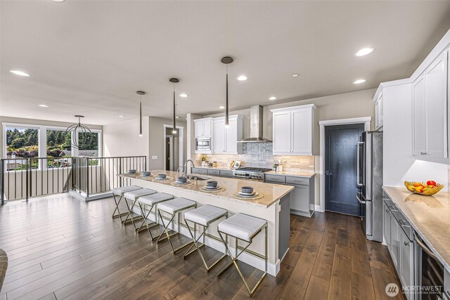4888 194th Ave SE, Issaquah, WA 98027 - kitchen with a sink, tasteful backsplash, appliances with stainless steel finishes, wall chimney range hood, and a breakfast bar area