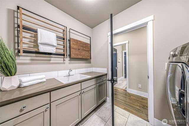 4888 194th Ave SE, Issaquah, WA 98027 - laundry room with light tile patterned floors, a sink, baseboards, cabinet space, and washer / clothes dryer