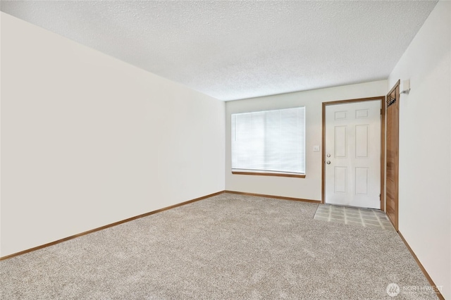 empty room featuring a textured ceiling, carpet flooring, and baseboards
