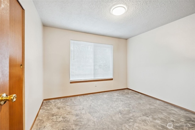unfurnished room featuring a textured ceiling, carpet floors, and baseboards