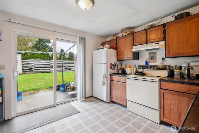 kitchen featuring dark countertops, brown cabinets, white appliances, and under cabinet range hood