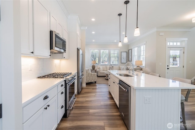 kitchen featuring a sink, open floor plan, a breakfast bar, high quality appliances, and ornamental molding