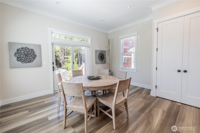 dining room featuring baseboards, crown molding, and light wood finished floors