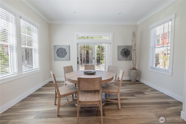 dining area featuring light wood-style flooring, crown molding, and baseboards