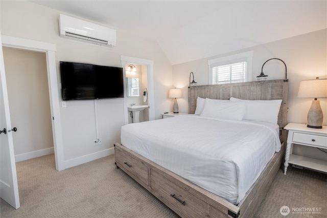 bedroom featuring vaulted ceiling, connected bathroom, a wall mounted AC, light carpet, and baseboards