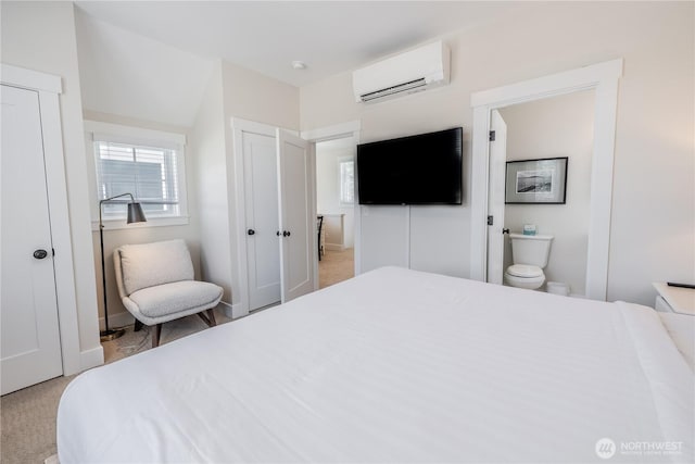 carpeted bedroom featuring a wall mounted AC and connected bathroom