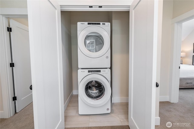 washroom with stacked washer / drying machine, baseboards, carpet, and laundry area
