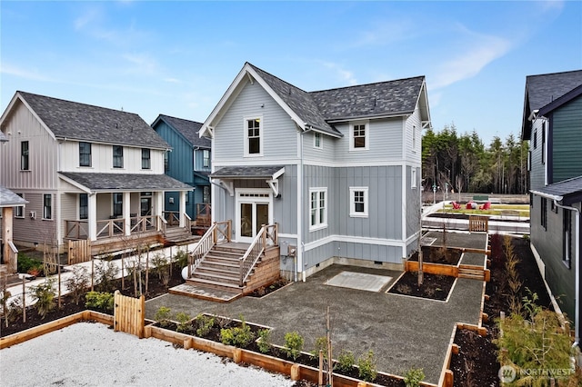 back of property featuring board and batten siding, a garden, and roof with shingles