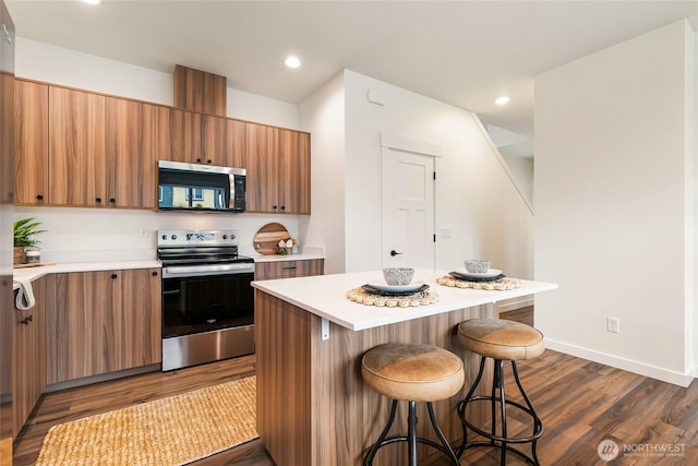 4226 Melrose Ln, Bellingham, WA 98226 - kitchen featuring stainless steel appliances, a breakfast bar, light countertops, dark wood-style flooring, and recessed lighting