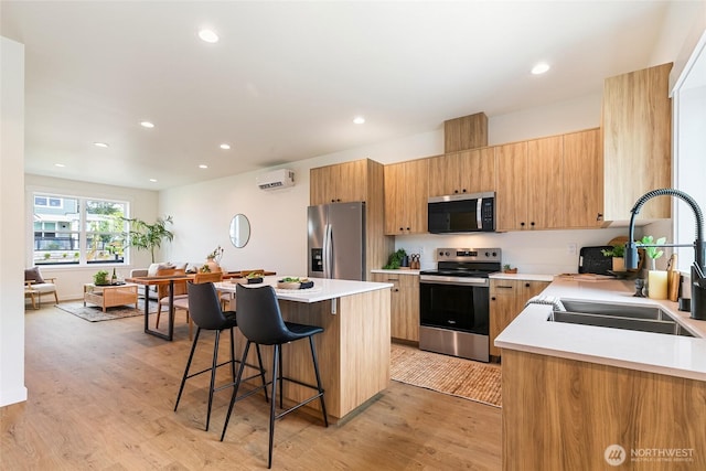 4228 Melrose Ln, Bellingham, WA 98226 - kitchen with appliances with stainless steel finishes, a wall unit AC, a kitchen breakfast bar, light wood-style floors, and recessed lighting