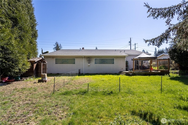 back of property featuring fence, a gazebo, and a lawn