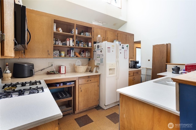 kitchen with backsplash, white refrigerator with ice dispenser, light countertops, and a sink