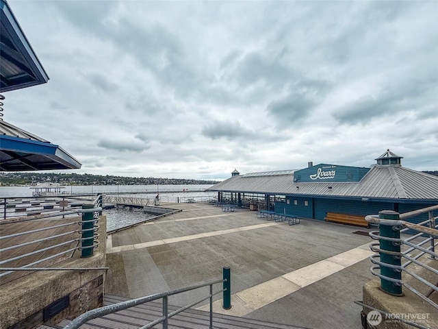 view of patio with a water view and a dock