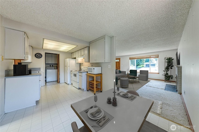living area featuring a textured ceiling, light tile patterned floors, and washer / dryer