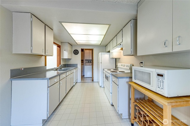 kitchen with white appliances, washer / clothes dryer, under cabinet range hood, a sink, and light tile patterned floors