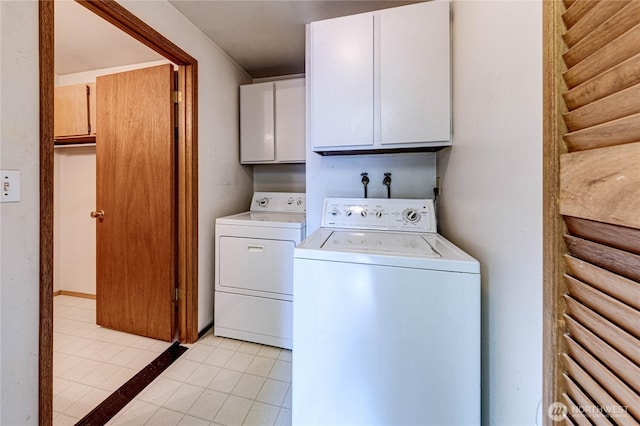 clothes washing area featuring cabinet space, light tile patterned floors, and washing machine and clothes dryer