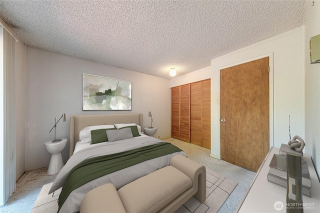 bedroom featuring light colored carpet, a textured ceiling, and a closet