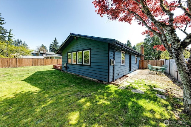rear view of property with a lawn, a fenced backyard, and a patio area