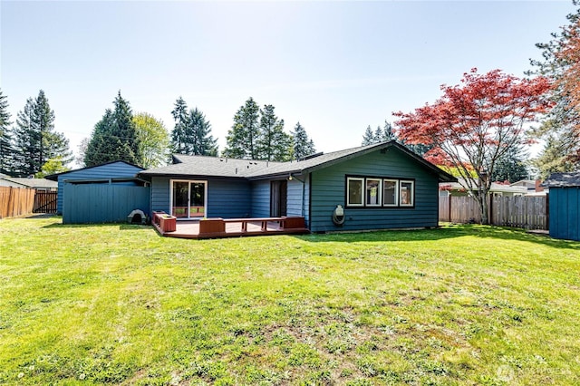 back of house with a storage shed, a deck, an outbuilding, a fenced backyard, and a yard